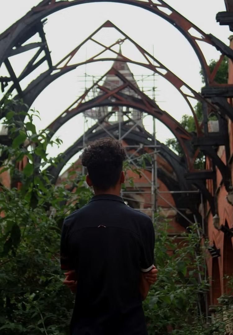 A young person looks up at the fire-damaged roof arches of St Michael's church