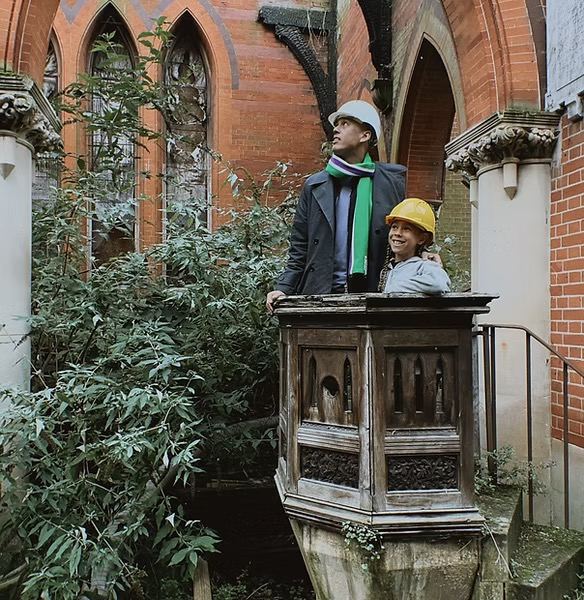 Two visitors in hard hats at the old pulpit inside St Michael's