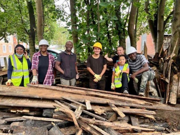 Volunteers in hard hats behind a pile of burnt timber