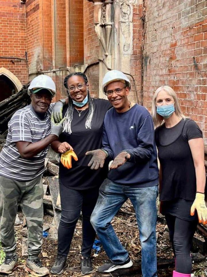 Four volunteers in work gloves inside the church ruins