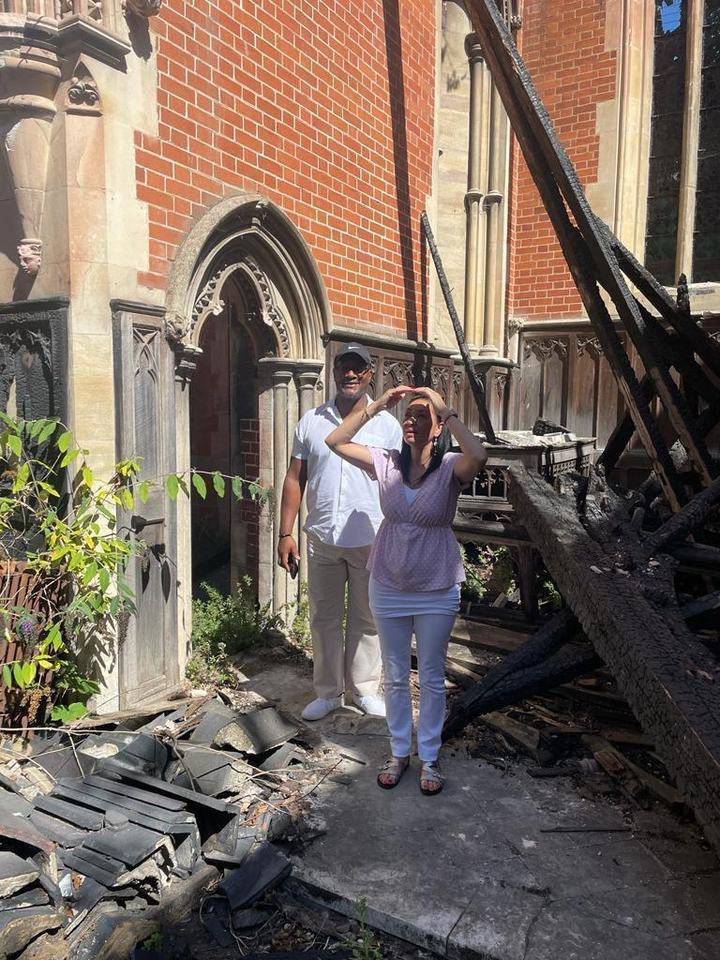 Two visitors look up at the burnt roof timbers