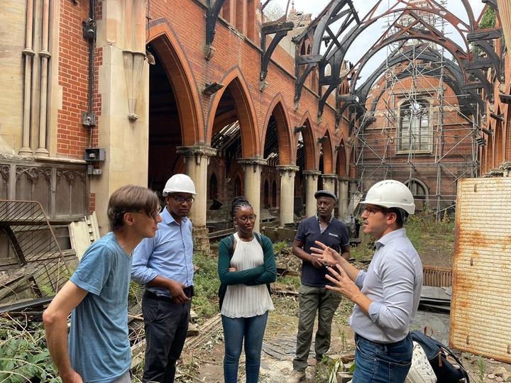 A group listens to a man in a hard hat explaining plans inside the church
