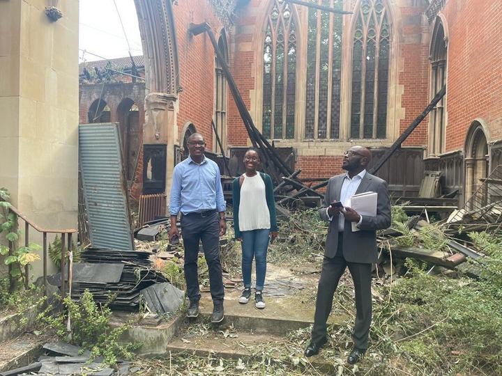 Three people stand among the debris inside the church