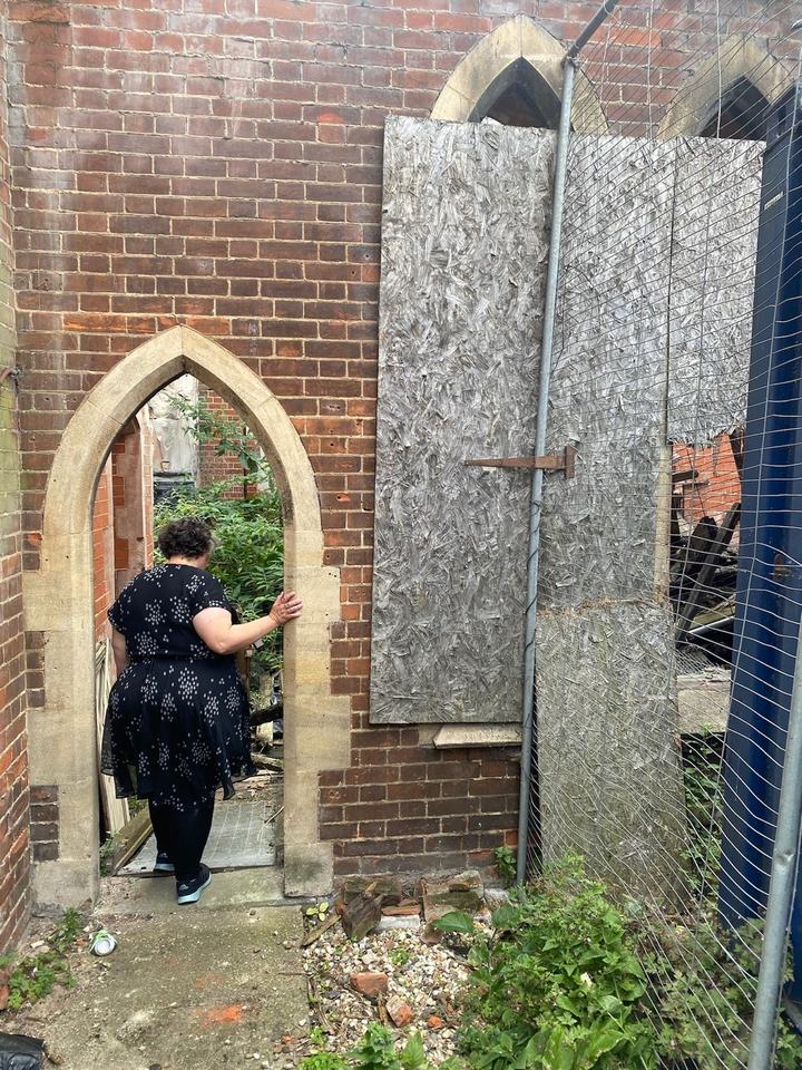 A woman walks through a stone arched doorway into the church